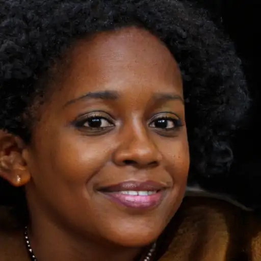A young woman in her 20s smiling as she touches her smooth, frizz-free hair.