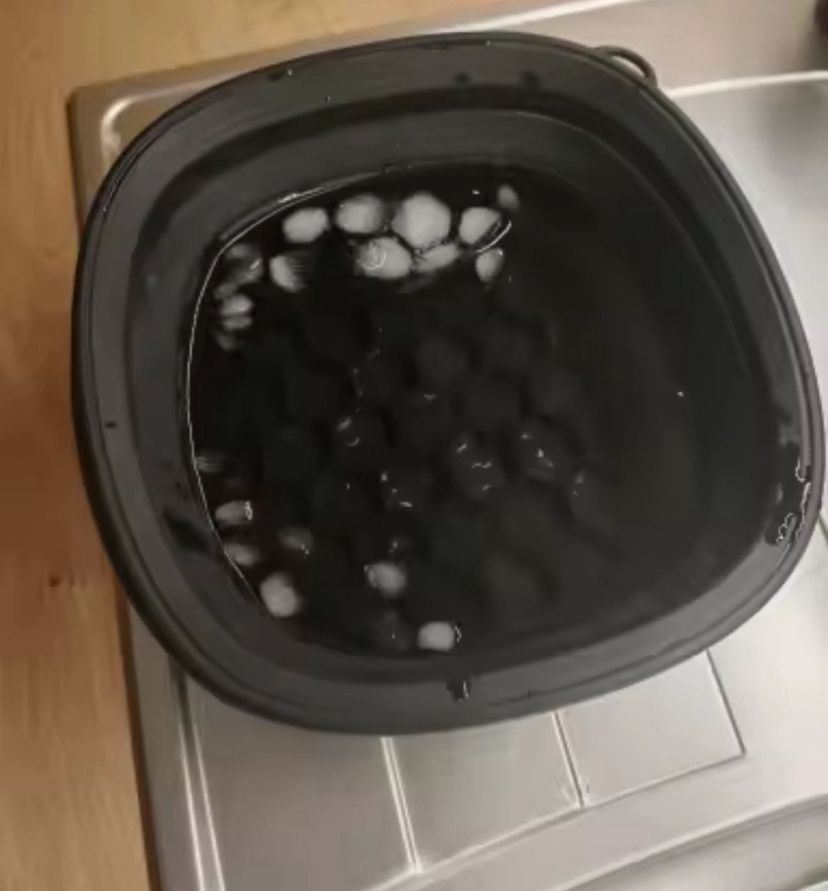 A person enjoying a refreshing ice facial at home with a foldable ice bath bowl.