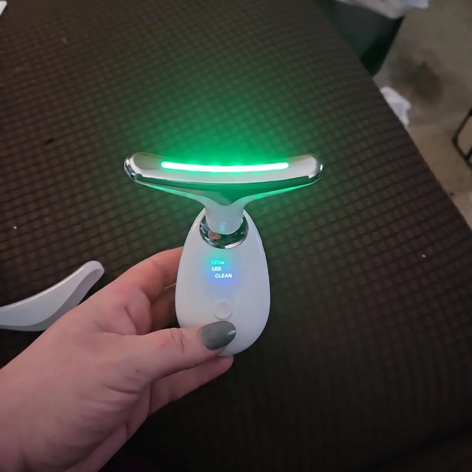 Woman admiring her lifted jawline using The Neck Sculptor at home