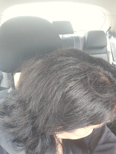 Image d'une femme souriante tenant une bouteille de gummies Good Hair