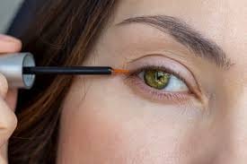Woman applying serum to lashes at night