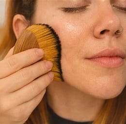 Close-up of a woman gently massaging her face with a beauty tool for better absorption.