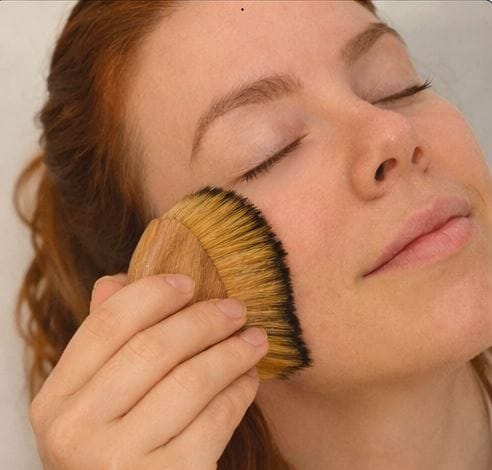 Woman enjoying a relaxing facial massage with a manual sculpting tool for circulation.