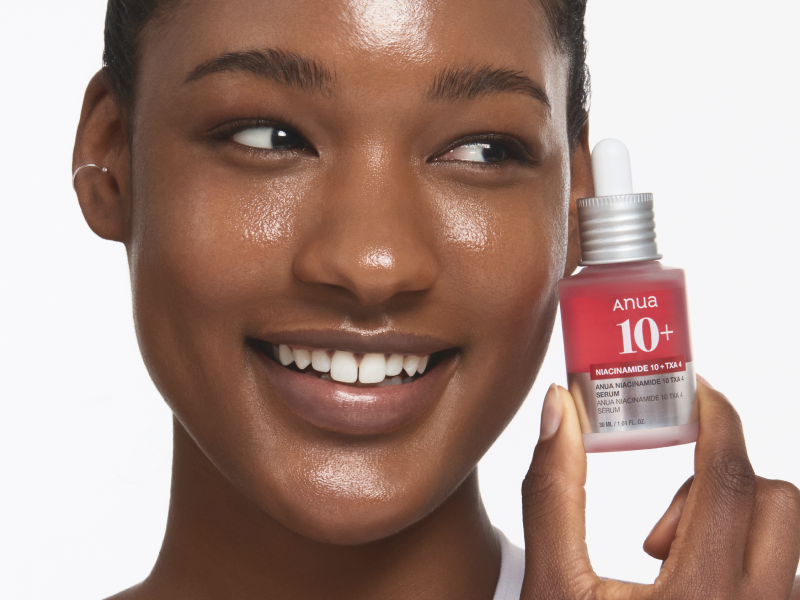 Woman with glowing skin holding a serum bottle