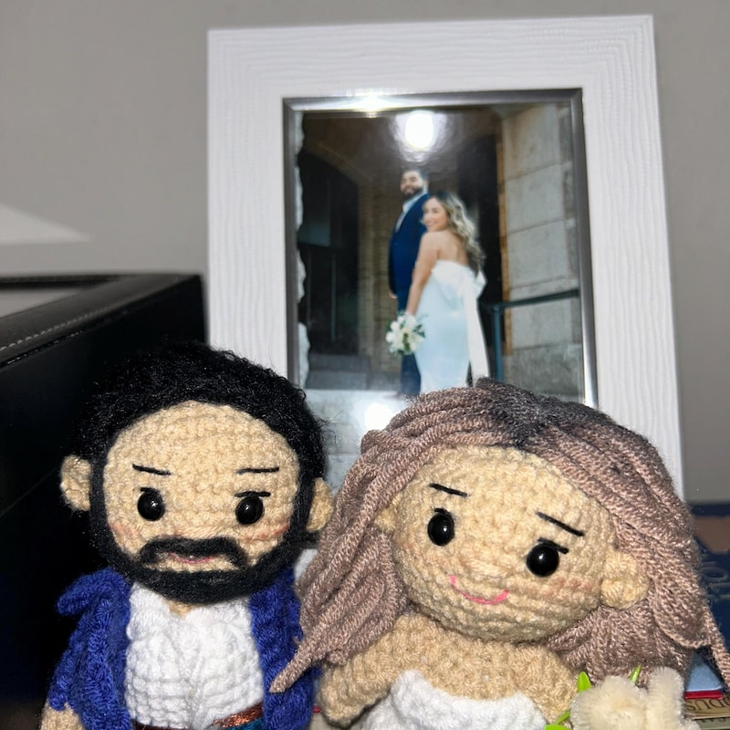 Couple holding custom crochet dolls representing them