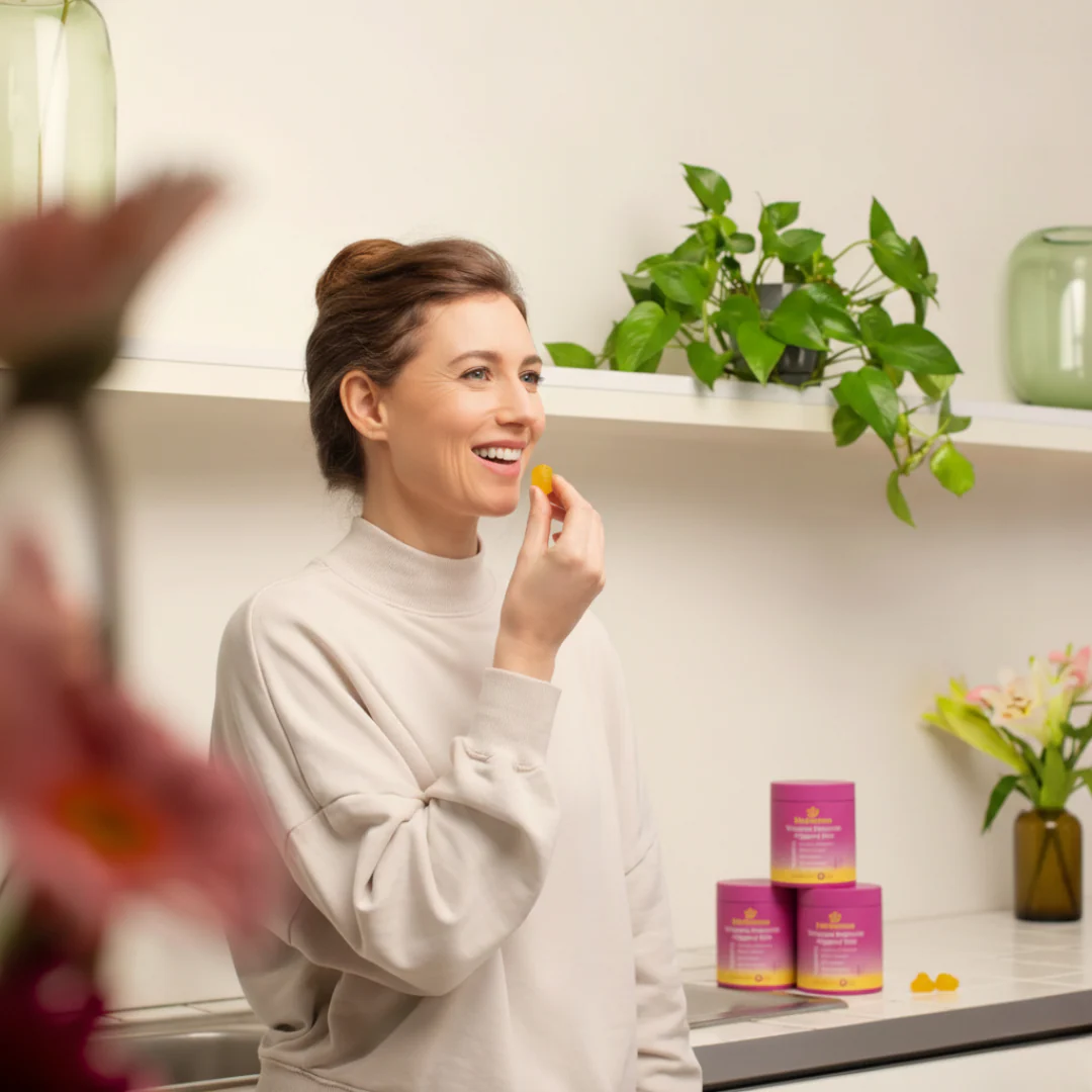 Mujer sonriendo y sosteniendo un frasco de gomitas probióticas