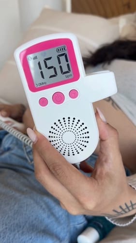 امرأة حامل تبتسم أثناء استخدام جهاز الاستماع إلى نبضات الجنين