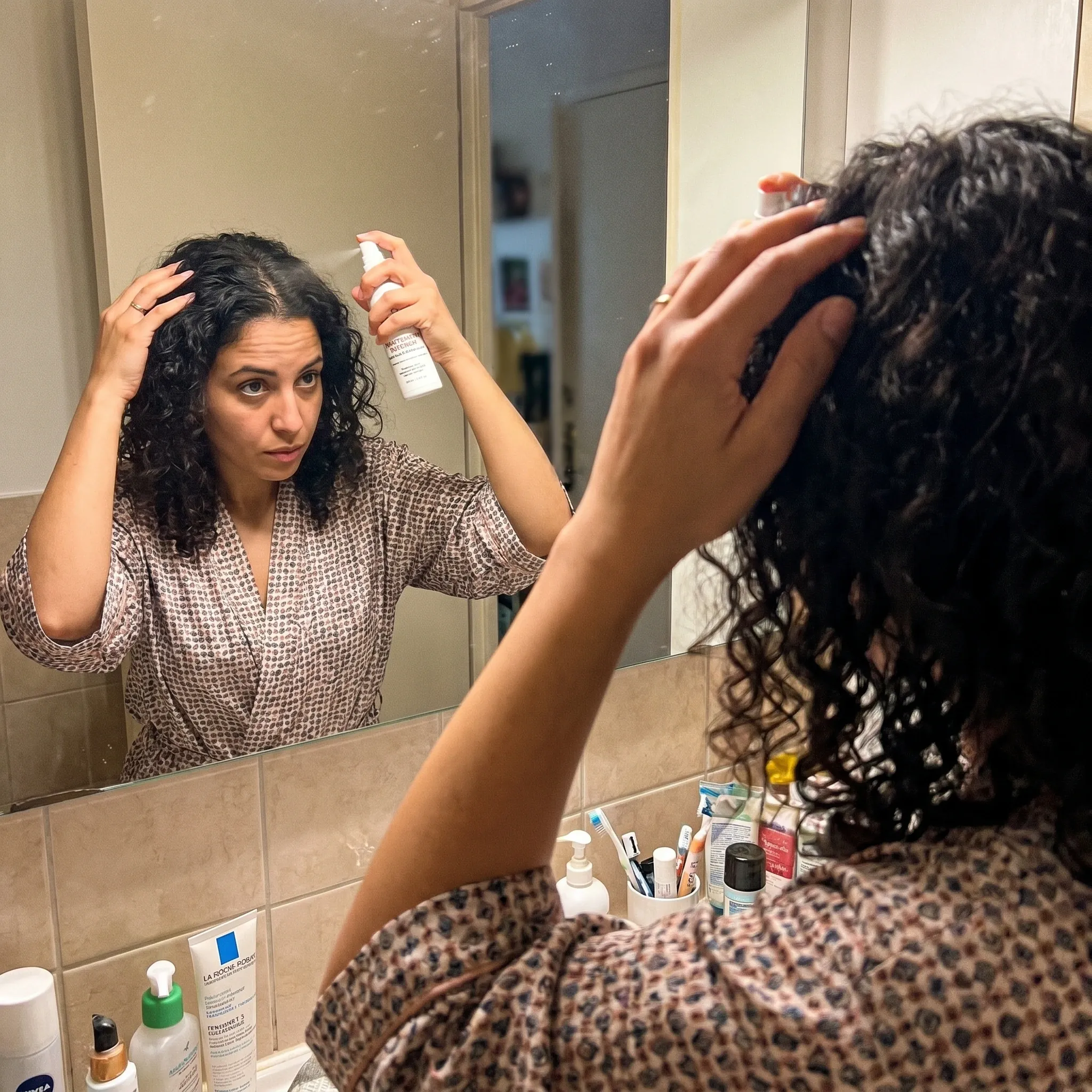 Femme souriante tenant une mèche de cheveux plus dense.